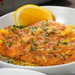 Crispy fried chicken on spaghetti with lemon and parsley garnish, a delicious poultry dish.